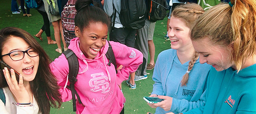 Diverse school girls pose for a photo outdoors. Young Black girl smiles at the camera.