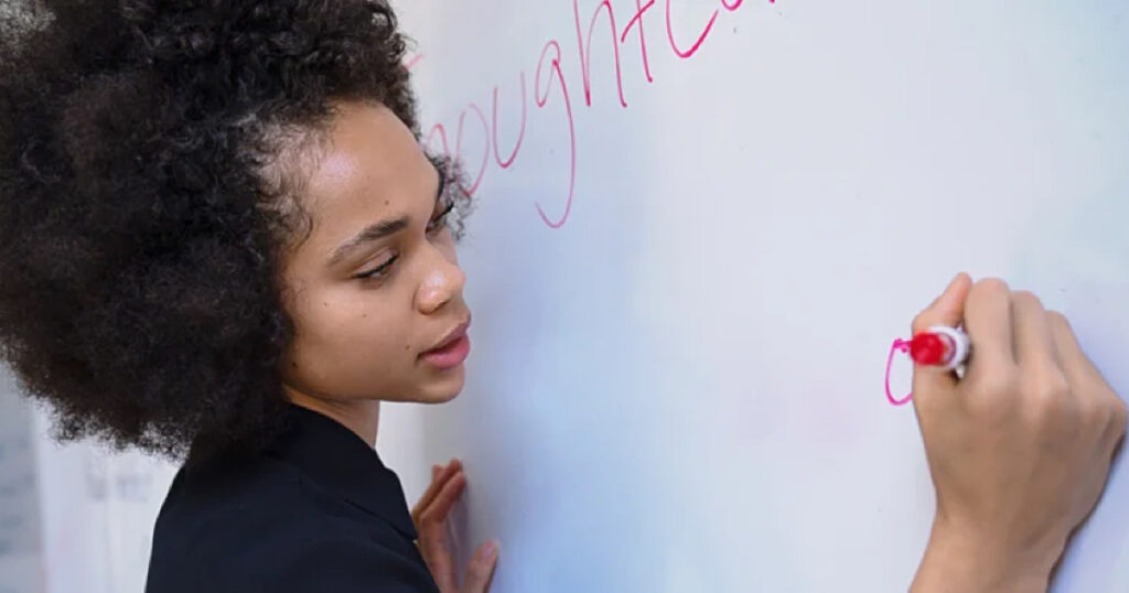 Young Black Woman Teacher writing on a white board