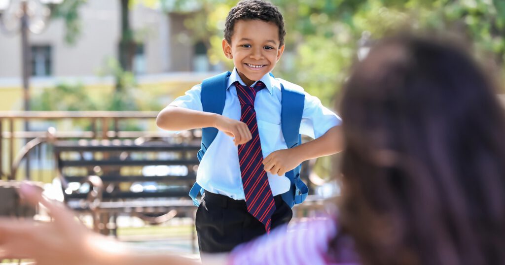 Boy dressed in a school uniform running into a woman's arms after school