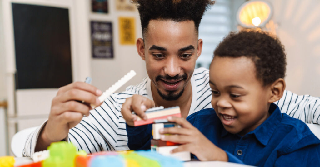 Happy african american boy playing with her smiling father at home