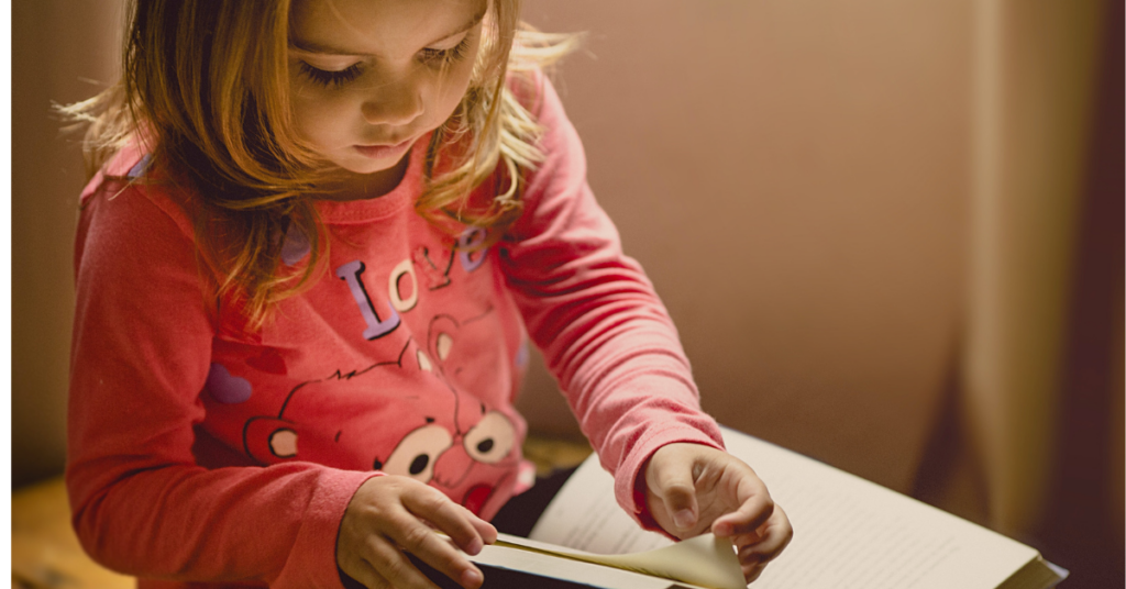 Young child reading a book. Photo by Jonathan Borba on Unsplash.