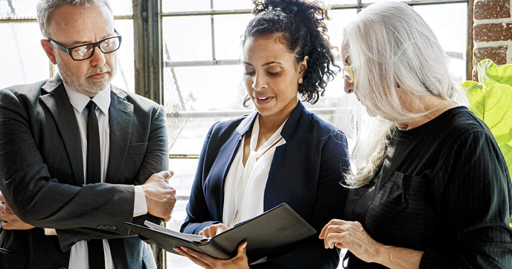 Diverse business people/board members discussing together in front of a window