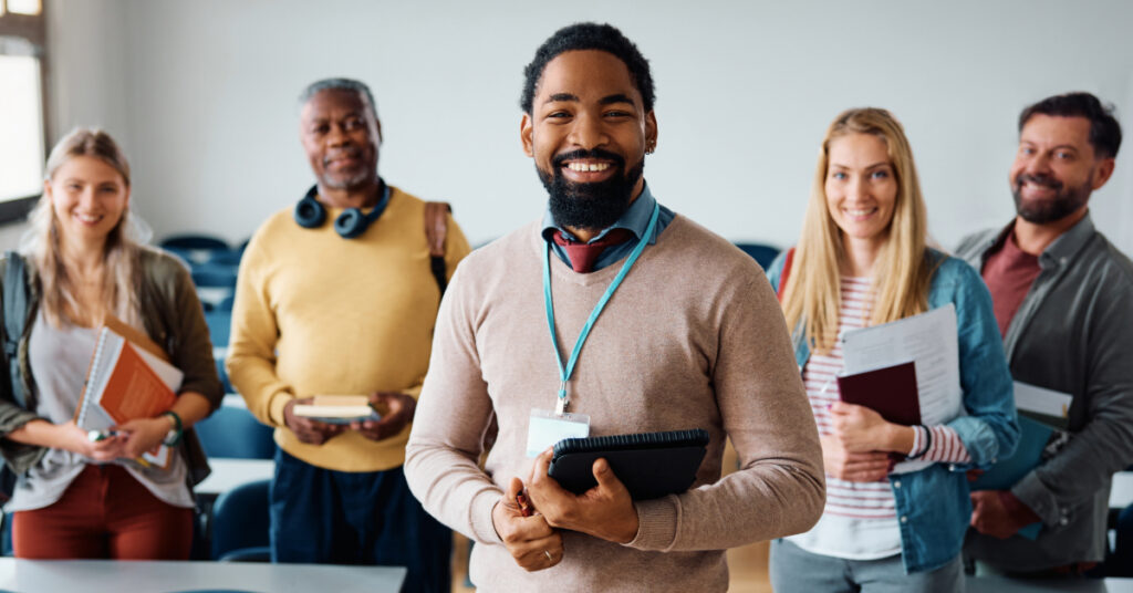 Happy African American professor and his adult students in lecture hall looking at camera.