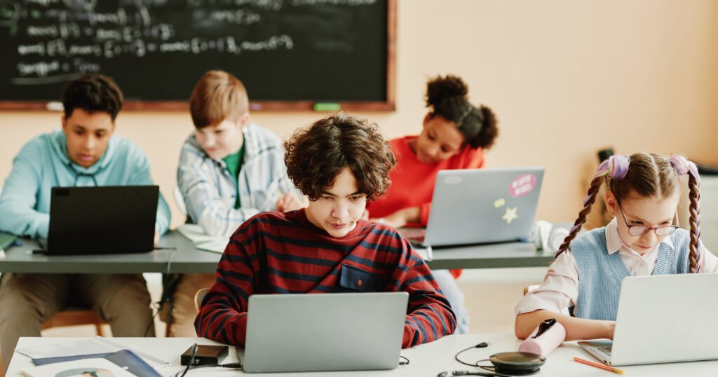 Group of school children using laptops in class