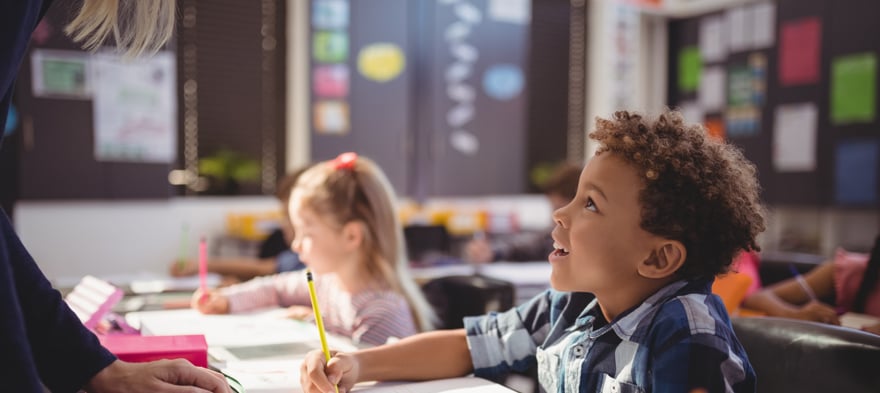 Classroom with a boy in the foreground looking up, encouraged.