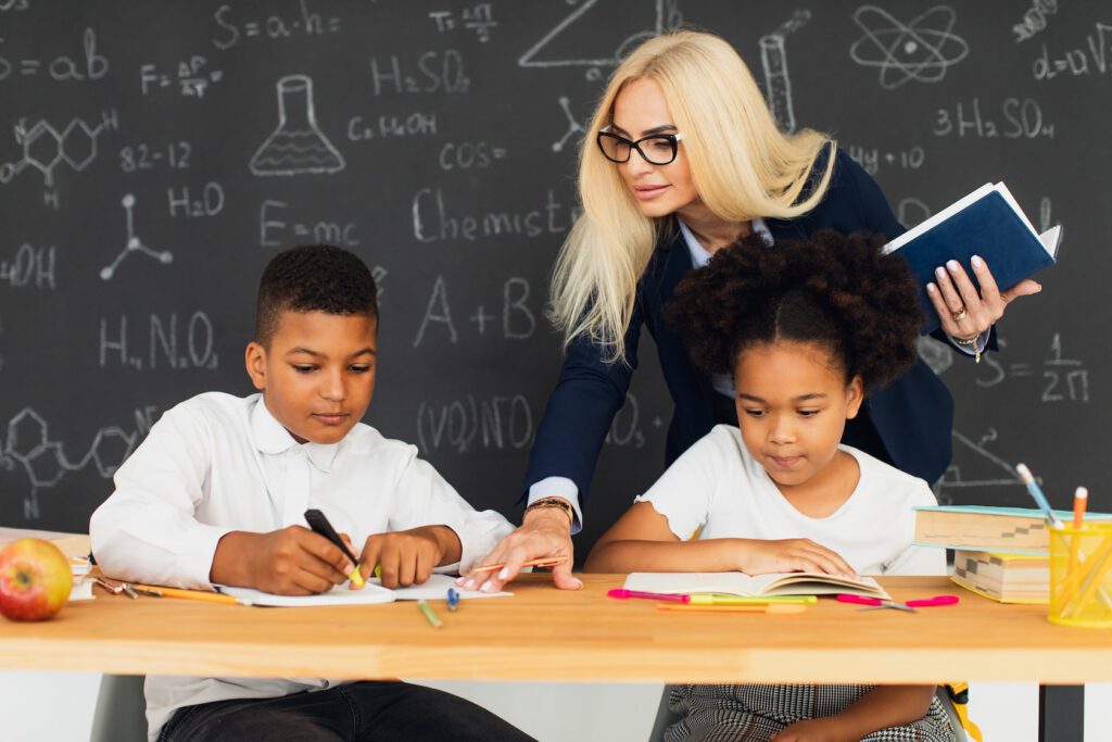 A white female teacher teaching two Black students
