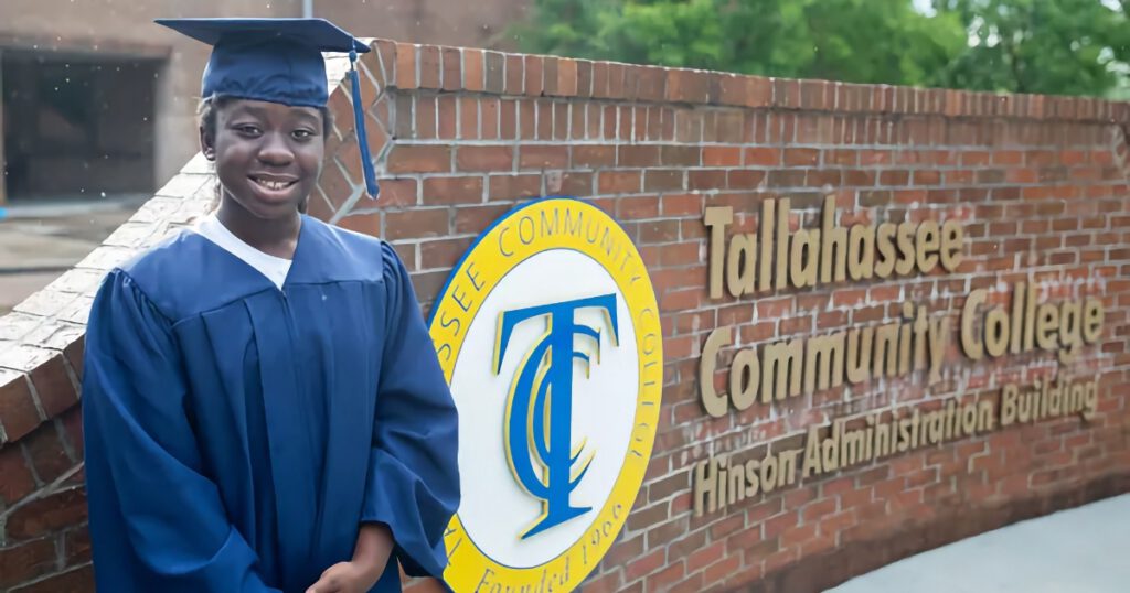 E’leese Shelton in blue graduation regalia standing in front of a wall at Tallavana Christian School, Florida