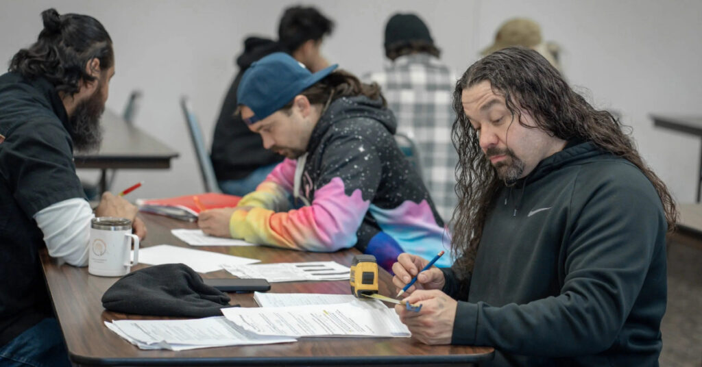 Keith Perkins, foreground, works through an algorithm for calculating ladder rung spacing in Linn-Benton Community College’s math for welders class.