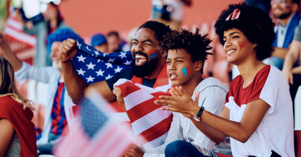 Happy black family cheering for USA during sports match at the stadium.