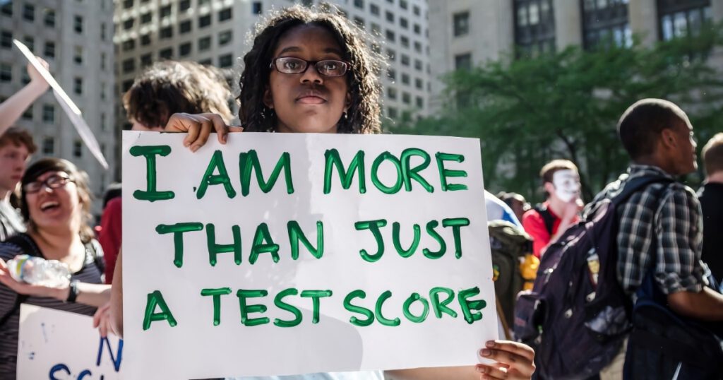 Young Black girl holding a sign protesting standardized testing; Other youth in background.