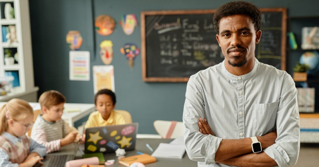 Portrait of Smiling African American Male Teacher in Primary School Classroom