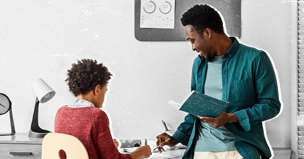 Black male teacher with student at a desk
