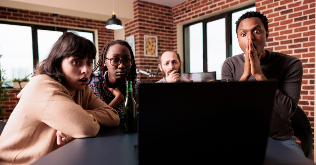 Worried multiethnic friends sitting at home in living room while reading upsetting news events on laptop
