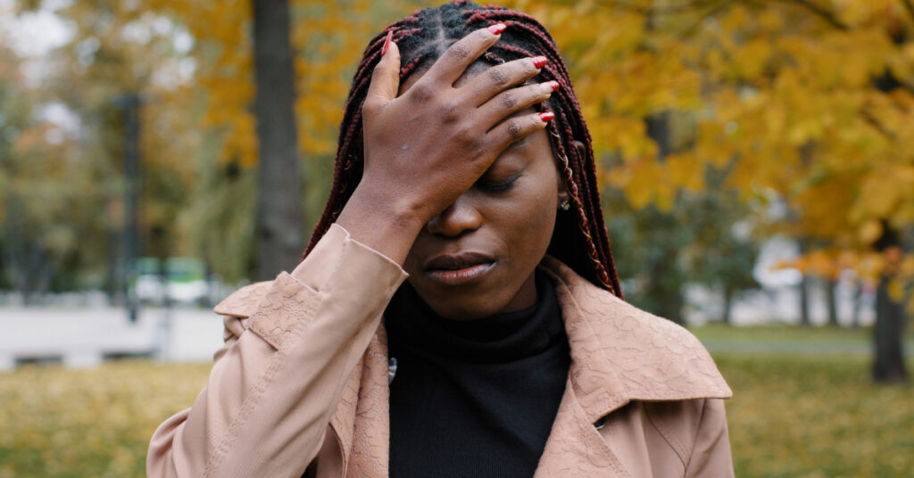 Young distressed Black woman puts palm on head in shame due to mistake