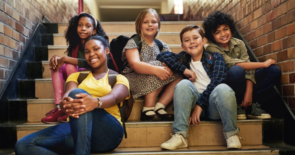 Full length shot of a diverse group of children sitting together on the staircase at school