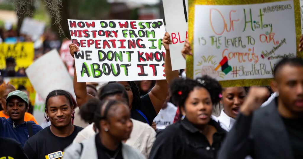 Black youth walking in a protest march against Ron DeSantis' efforts to minimize diversity in education