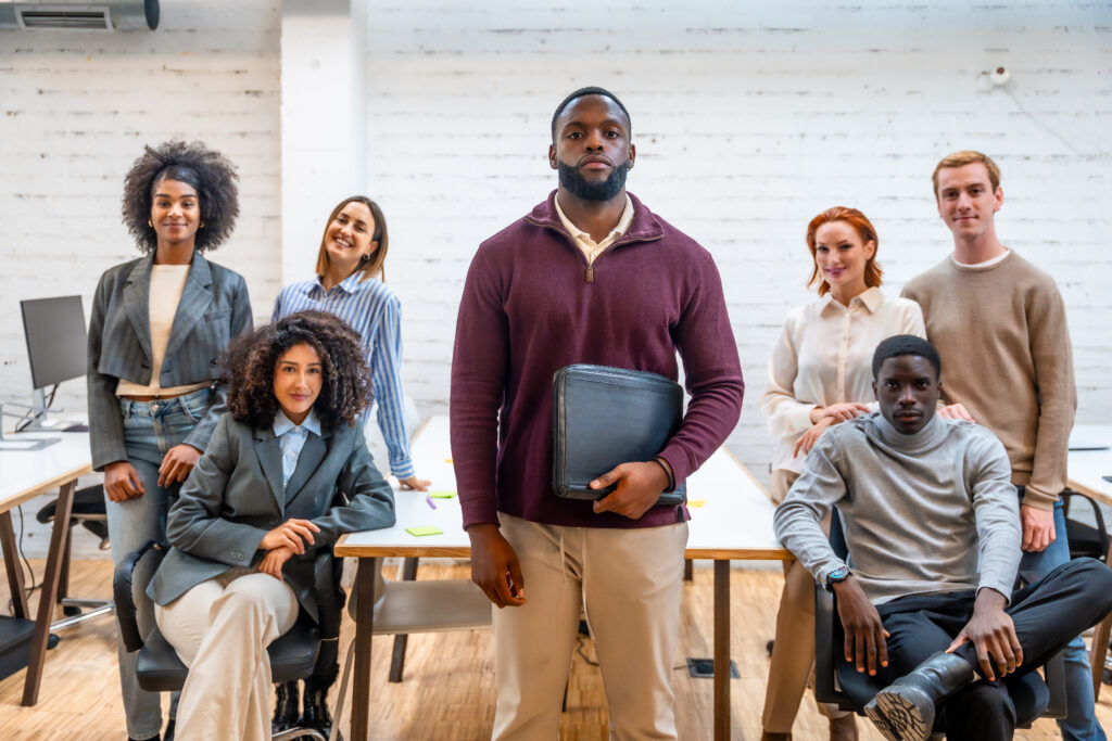 Black male teacher standing surrounded by colleagues