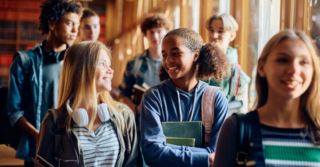 Happy African American student and her friends communicating while leaving the classroom after the lecture.